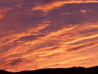 Fiery sunset over Mull, Scotland, with lone telegraph poles silhouetted against bright orange clouds