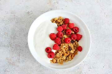a bowl of raspberries and yogurt and granola top view