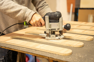 Ouvrier artisan blanc expérimenté en train d'utiliser une défonceuse à bois pour fabriquer un meuble dans son atelier © Thomas
