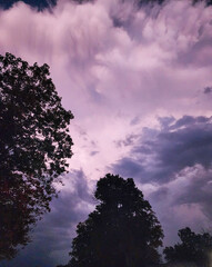 Moody thunderstorm clouds at dusk. A storm moving through over the trees in autumn.