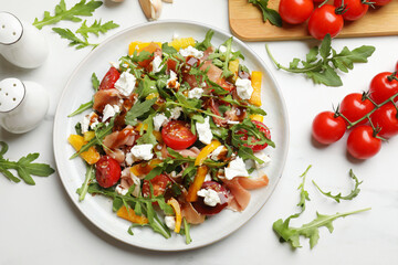 Tasty salad with arugula, cheese and vegetables on white table, flat lay