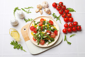 Tasty salad with arugula, cheese and vegetables on white tiled table, flat lay