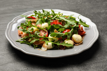 Tasty salad with arugula on dark textured table, closeup