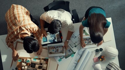Top view of project manager working together to brainstorm house design while standing around...