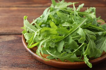 Fresh green arugula leaves on wooden table, closeup