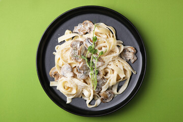 Delicious pasta with mushrooms on light green background, top view