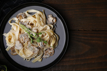 Delicious pasta with mushrooms on wooden table, top view. Space for text
