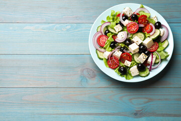 Delicious salad with feta cheese on blue wooden table, top view. Space for text