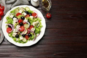 Delicious salad with feta cheese and ingredients on wooden table, flat lay. Space for text