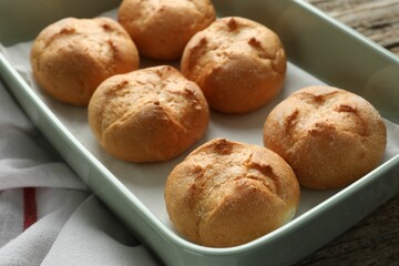 Homemade tasty buns in baking dish on wooden table, closeup