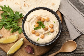 Delicious hummus with chickpeas and pita served on wooden table, flat lay