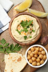Delicious hummus with parsley, paprika, pita, chickpeas and lemon on table, top view