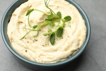 Delicious hummus in bowl on grey table, closeup