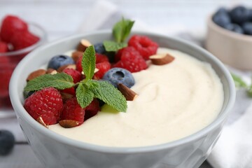 Tasty cooked semolina porridge with almonds, berries and mint on table, closeup