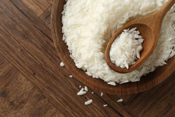 White soy wax flakes in bowl and spoon on wooden table, top view