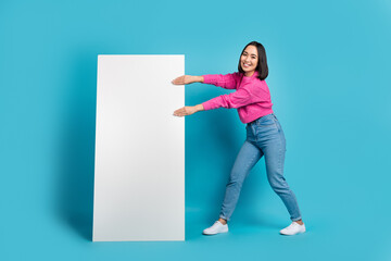 Full body photo of excited filipino lady hands pull huge empty space smart phone isolated on blue color background