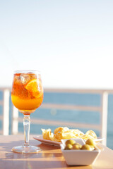 Aperol spritz cocktail glasses with olives and potatoes chips aperitif, very Mediterranean. Sea...