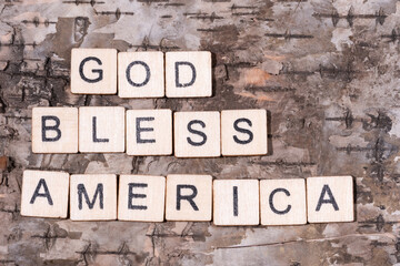 Christian religious background concept. God Bless America written with wooden block letters on natural wood bark background