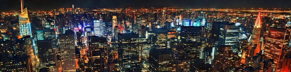 Obraz premium City Lights Aglow: A panoramic view of a bustling metropolis at night, the buildings illuminated in a myriad of colors.