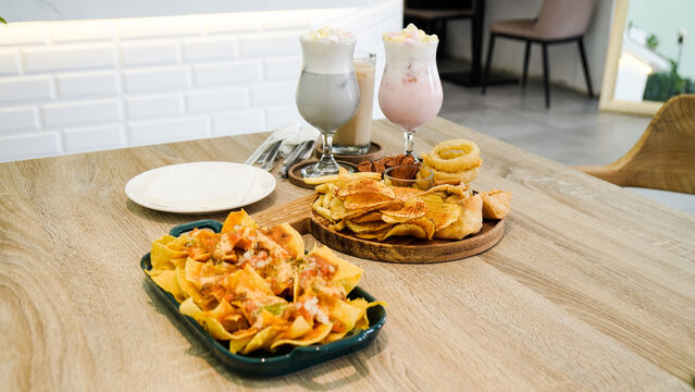The side dish menu at the cafe includes French fries, chicken wings, sausages, onion rings, and nacos, and there are two glasses of drinks behind them