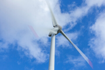 Windrad in Bewegung mit Bewegungsunschärfe vor blauem Himmel mit Wolken