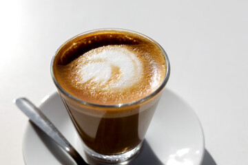 Traditional espresso coffee in cup on white table, top view.
