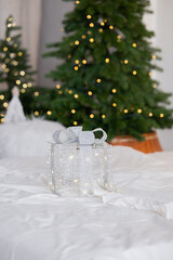 Beautifully wrapped gift on a bed adorned with Christmas trees and lights