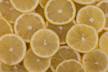 Yellow sliced lemons places on a table overlapping each other. Background texture of fresh yellow fruit. 