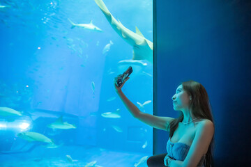 Woman selfie at a cafe table in the blue aquarium background. Okinawa