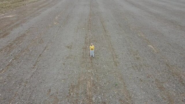 Mujer parada en tierra cosechada en campo, con rastrojo de ma&iacute;z