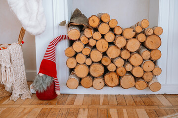 Cozy holiday decor with stacked firewood and a festive gnome in a warm room