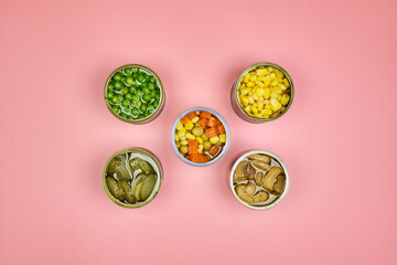 Very colorful canned vegetables, in a zenithal or top shot with a pink background and space for text