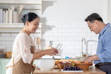 A woman prepares fresh vegetables in a cozy kitchen, while a man assists in the background. The scene emphasizes a warm and healthy lifestyle with a focus on fresh produce and home cooking.