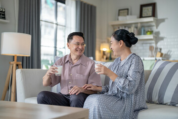 An elderly couple enjoys a peaceful moment at home, sharing smiles and drinks. The warm and cozy atmosphere emphasizes their deep connection, happiness, and the comfort of spending time together.