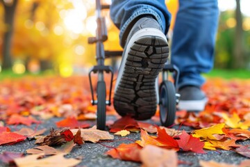 Fototapeta premium A person walking on a path covered with colorful autumn leaves, using a walker, showcasing the beauty of fall.