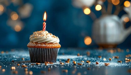 Delicious vanilla cupcake with white frosting, sprinkled with golden sugar and topped with a lit candle, on a bright black background, perfect for a birthday or holiday.