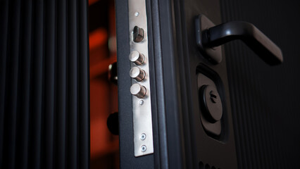 Extended door lock bolts on an open black armored entrance door. Locking mechanism on a door lock....