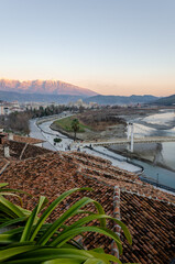  A panoramic view of Berat in Albania. The city is nestled against a backdrop of snow-capped Tomori mountain, with a traditional bridge spanning the Osumi river. 
