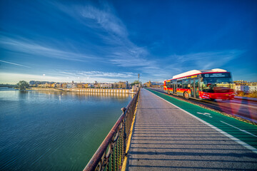 Seville, Spain, Jan 28 2021, City Bus Crossing Puente de Triana in Seville at Sunset