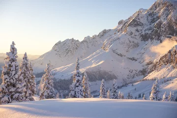 Snowy wintertime landscape and high iconic mountain peaks. Golden light on the mountain range and a cold wilderness foreground. © Olha Sydorenko