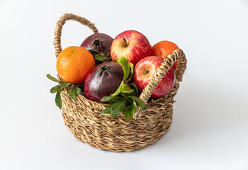Basket with fruits (apples, pomegranate, tangerine) on a white background
