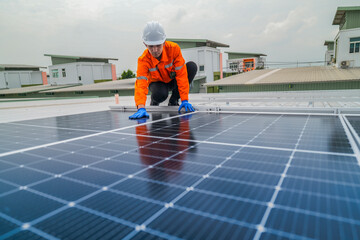 A worker in an orange safety jacket inspects solar panels on a rooftop, using a laptop to ensure...