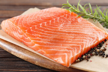 Piece of fresh salmon and spices on wooden table, closeup