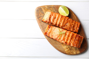 Delicious grilled salmon fillets with lime and rosemary on white wooden table, top view. Space for text