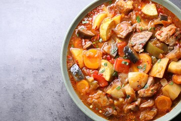 Delicious stew with vegetables in bowl on grey table, top view