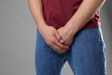 STD (sexually transmitted diseases). Man suffering from symptoms on grey background, closeup