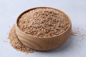 Buckwheat bran in bowl on light grey table, closeup