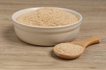 Oat bran in bowl and spoon on wooden table, closeup