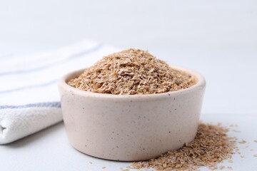 Buckwheat bran in bowl on white table, closeup