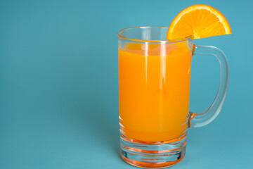 A glass of orange juice with a slice of orange. Orange juice with blue background. Orange juice blue background glass citrus. Blue orange juice with oranges and oranges on lifestyle a glass.